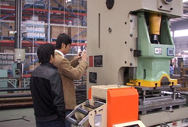 An SGS auditor (right) taking photos of product equipment.
