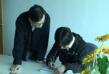 An SGS auditor (right) writing an Audit Report draft.